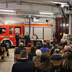 In der Fahrzeughalle der Feuerwehr Waldtrudering sitzen etwa 50 Gäste und folgen dem Bericht des scheidenden Vereinsvorstandes